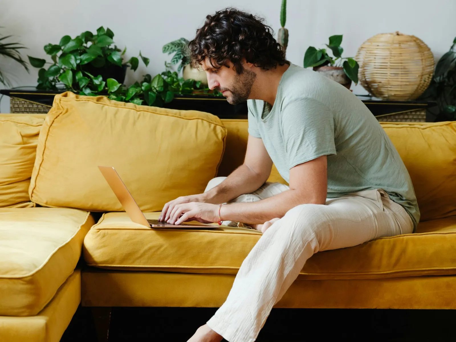 Ein Mann eröffnet mit einem Laptop entspannt vom Sofa aus online sein Depot – ohne Papierkram.